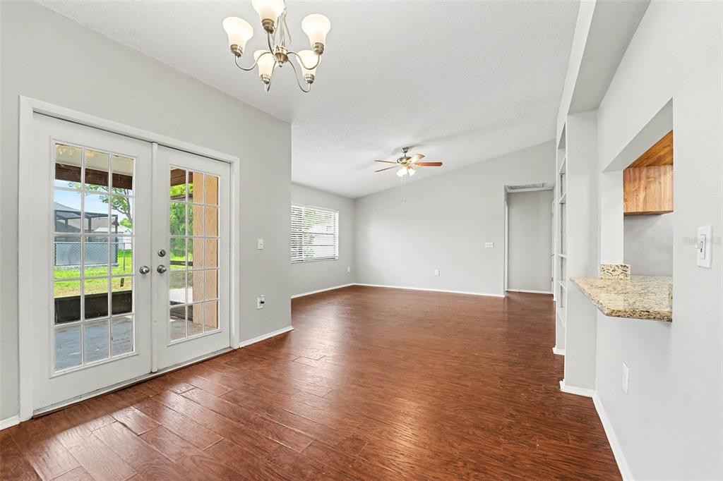 A dining area with wood-look floors, a chandelier, and glass doors leading to a patio — 11320 JACK RABBIT LANE, PORT RICHEY, FL