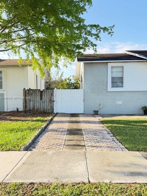 A paved walkway leads to a white wooden gate between two light-colored residential buildings — 9770 SW 210th St, Cutler Bay FL 33189, CUTLER BAY, FL