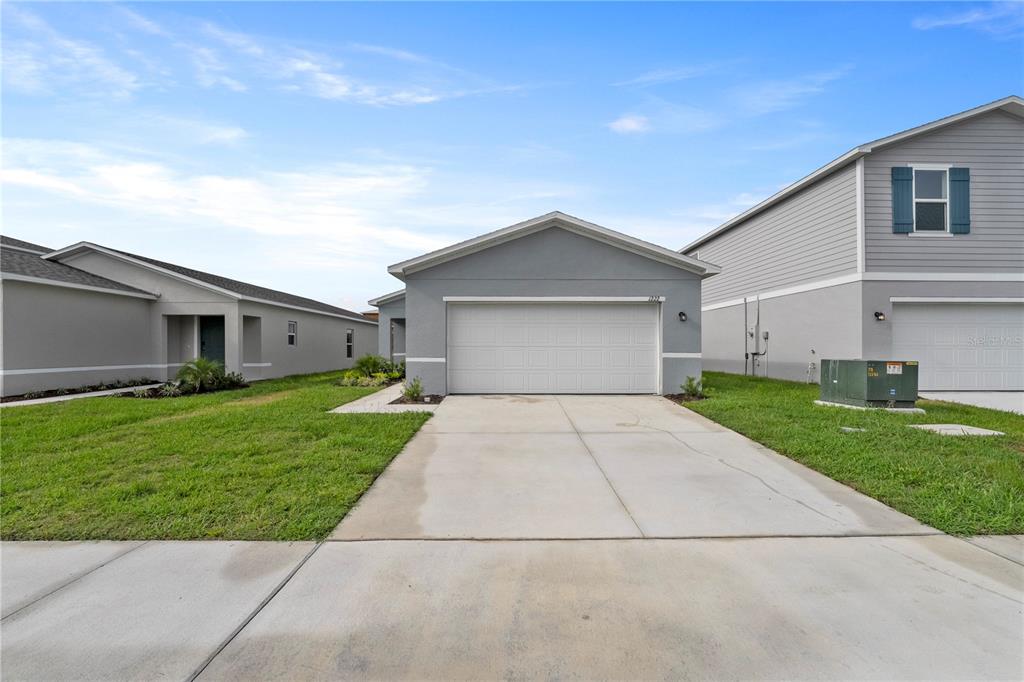 A single-story gray house with a two-car garage and a concrete driveway — 2077 GOLDEN BEAK DRIVE, EAGLE LAKE, FL
