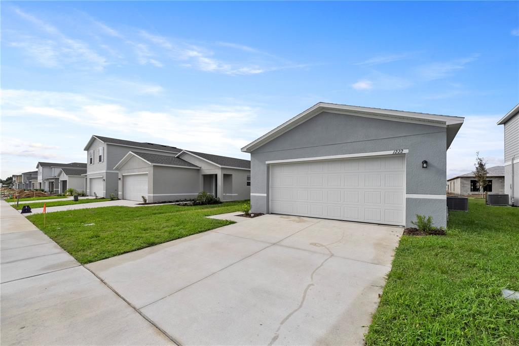 A gray single-story house with a white garage door and a concrete driveway — 2077 GOLDEN BEAK DRIVE, EAGLE LAKE, FL
