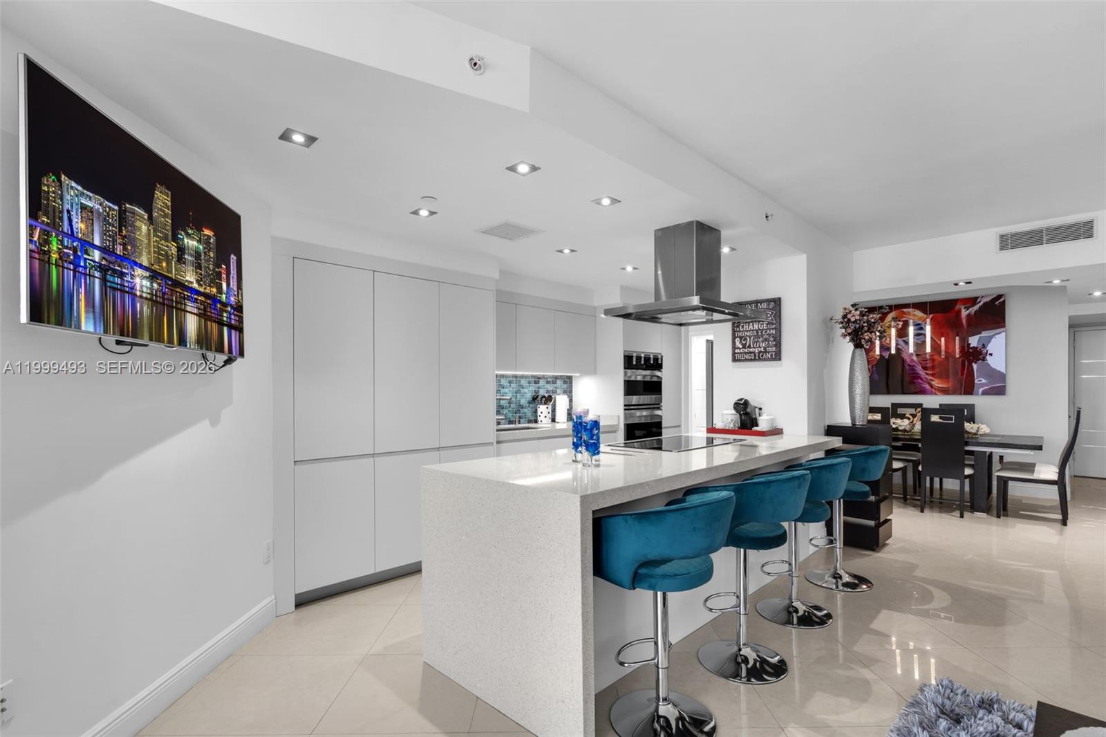 A modern kitchen features a white quartz island with blue velvet bar stools — 4775 Collins Ave # 3608, Miami Beach FL 33140, MIAMI BEACH, FL