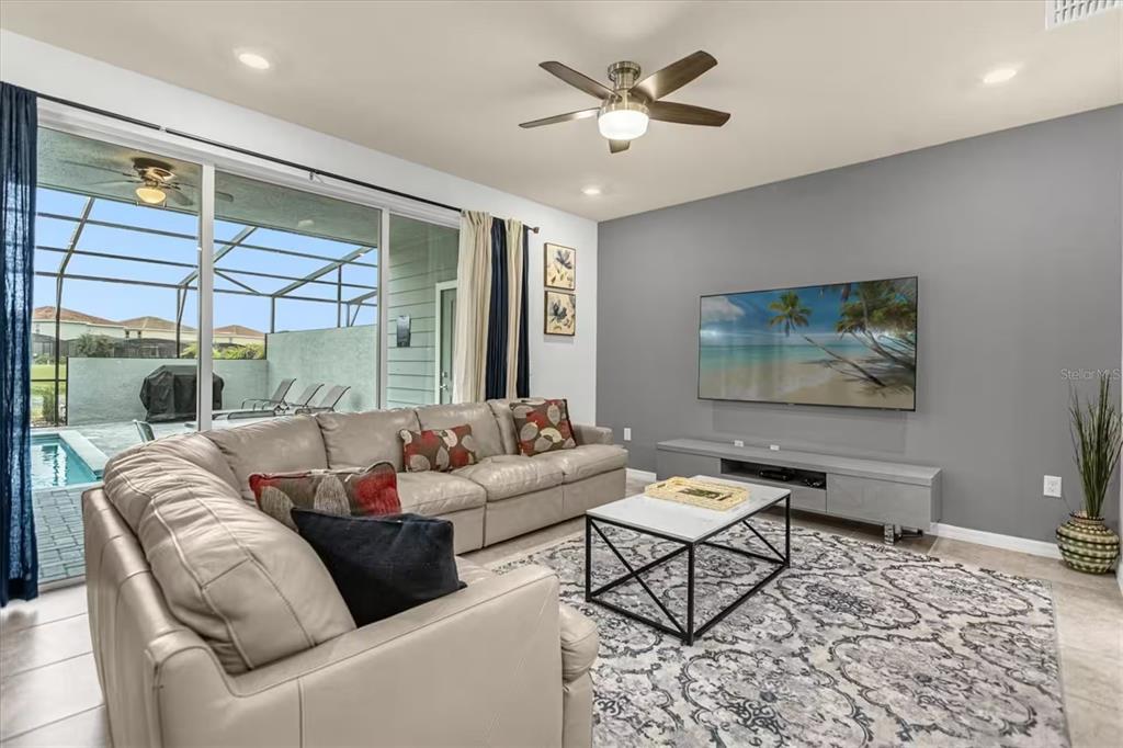 A living room features a large sectional sofa, a wall-mounted television, and sliding glass doors — 7542 OAK SPRING LANE, DAVENPORT, FL