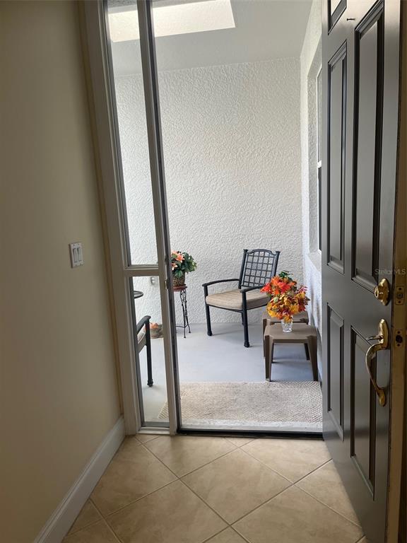 A view through an open door into a small, covered patio with tile flooring — 7245 CLEOPATRA DRIVE, LAND O LAKES, FL