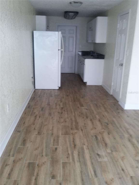 A kitchen features white cabinets, a white refrigerator, and wood-look flooring — 1710 S WASHINGTON AVENUE UNIT 16, TITUSVILLE, FL
