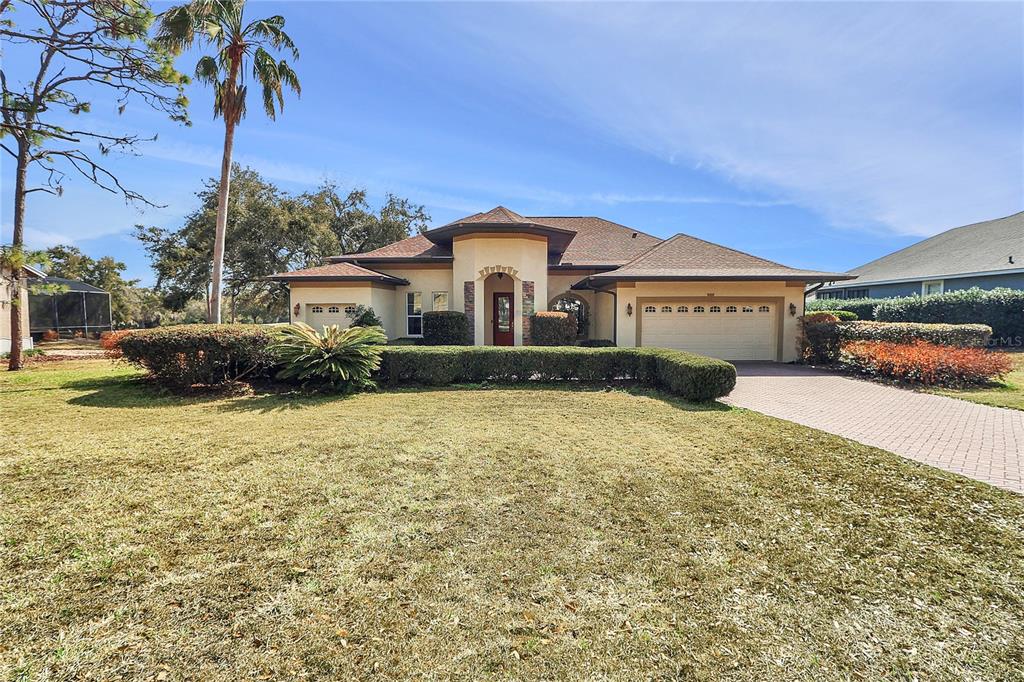 A single-story house with a beige stucco exterior, a tiled roof, and a paved driveway — 39644 HARBOR HILLS BOULEVARD, LADY LAKE, FL