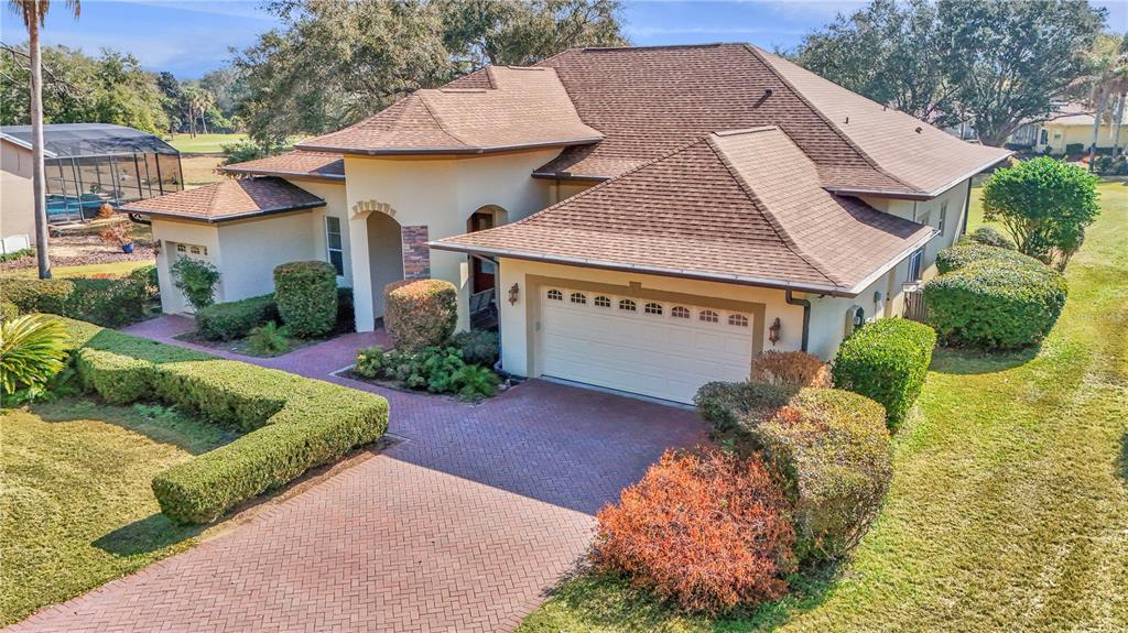 An aerial view of a single-story house with a brown shingled roof and brick driveway — 39644 HARBOR HILLS BOULEVARD, LADY LAKE, FL