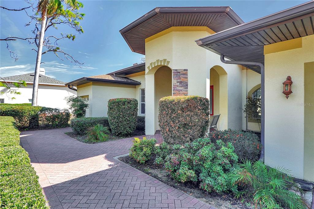 A paved walkway leads to the entrance of a house with stucco walls and landscaping — 39644 HARBOR HILLS BOULEVARD, LADY LAKE, FL