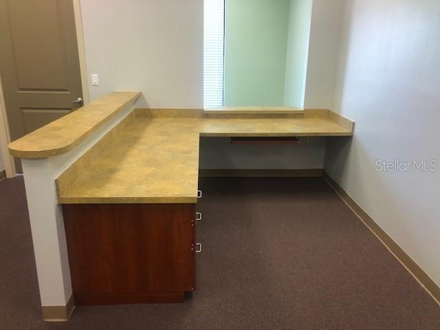 An L-shaped reception desk with a laminate countertop sits in a room with brown carpet — 22655 BAYSHORE ROAD UNIT 140, PORT CHARLOTTE, FL