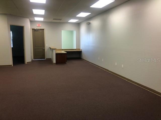 An office space features brown carpeting, a reception desk, and a doorway leading to another room — 22655 BAYSHORE ROAD UNIT 140, PORT CHARLOTTE, FL