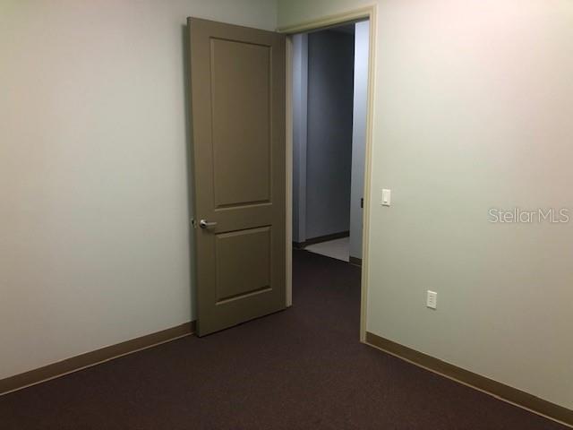An interior view shows a room with brown carpet, light-colored walls, and an open doorway — 22655 BAYSHORE ROAD UNIT 140, PORT CHARLOTTE, FL