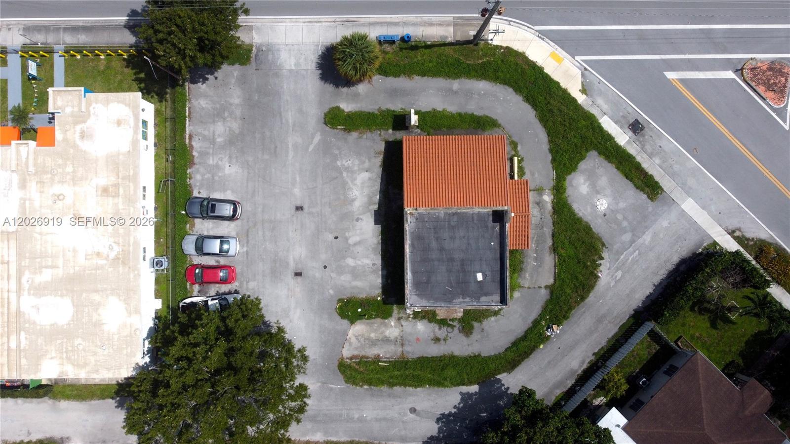 An aerial view shows a commercial building with a parking lot and surrounding greenery — 14100 W Dixie Hwy, North Miami FL 33161, NORTH MIAMI, FL