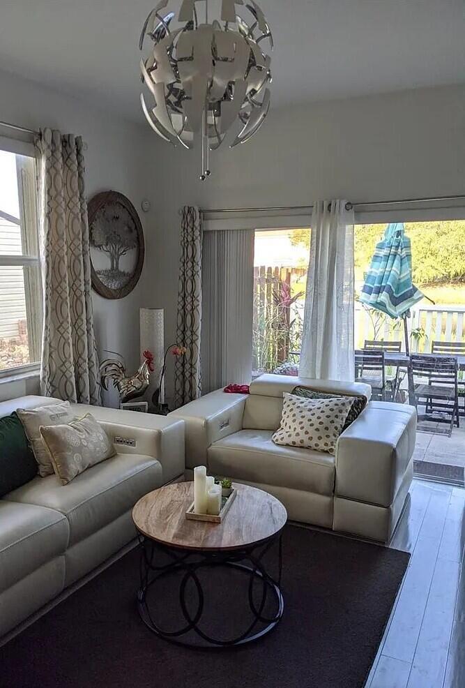 A living room features white leather furniture, a round wooden coffee table, and a chandelier — 1655 NE 33rd Road # 4, Homestead FL 33033, HOMESTEAD, FL