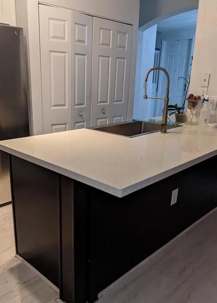 A kitchen island with a white countertop and dark base features an integrated sink — 1655 NE 33rd Road # 4, Homestead FL 33033, HOMESTEAD, FL