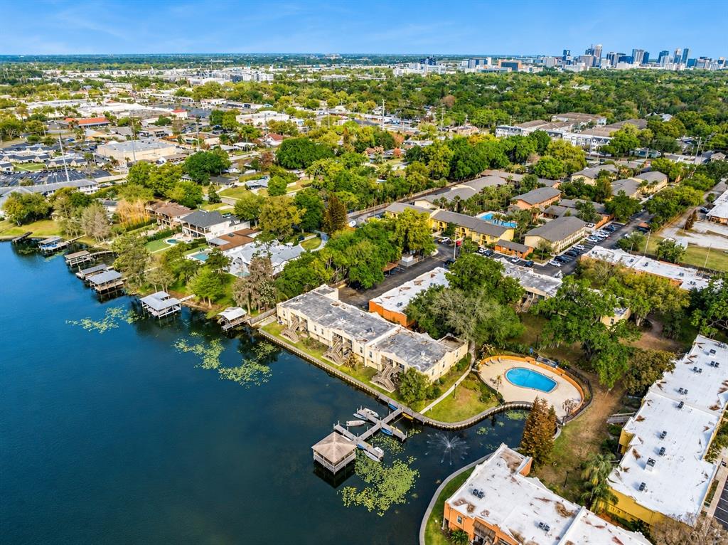 An aerial view shows apartment buildings along a lake with a dock and swimming pool — 754 E MICHIGAN STREET UNIT 185, ORLANDO, FL