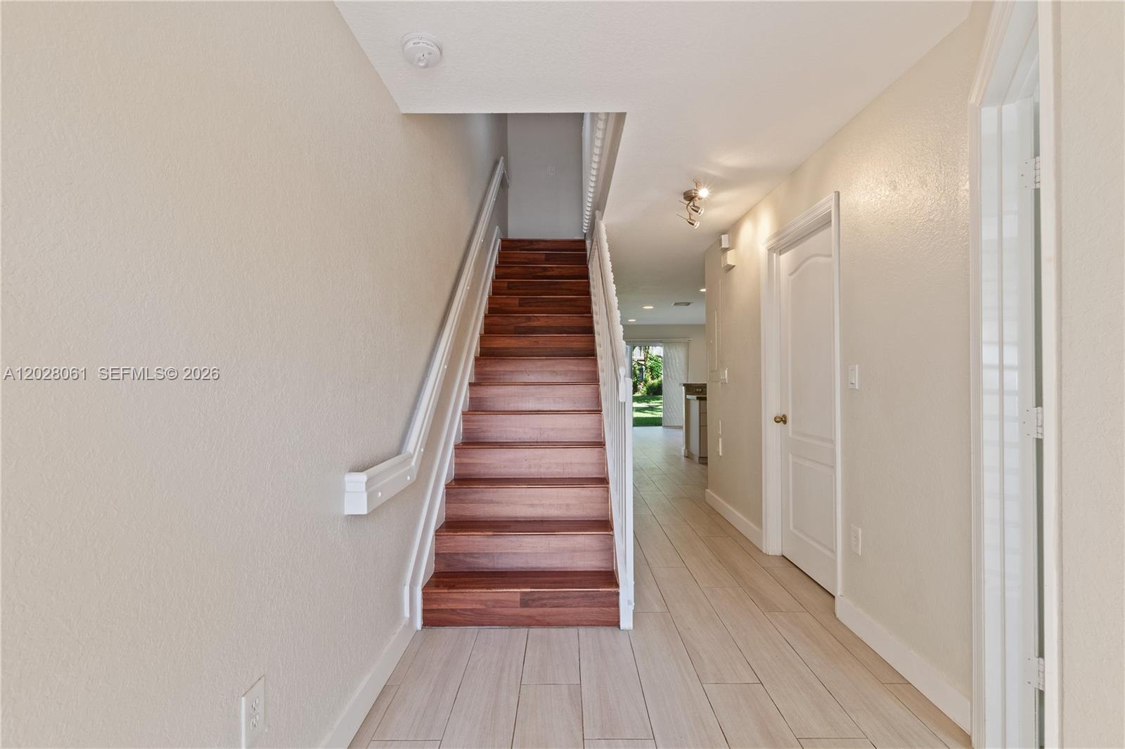 A staircase with wood treads leads upward in a hallway with light-colored tile flooring — 3126 SW 128th Ave # 157, Miramar FL 33027, MIRAMAR, FL