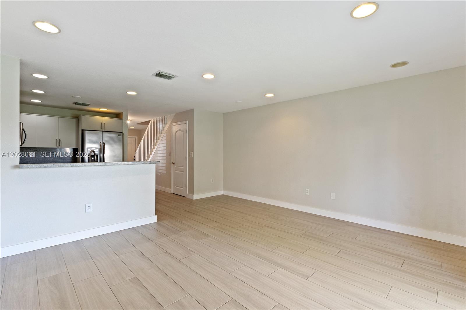 An open-concept living area features light wood-look tile flooring and a kitchen with stainless appliances — 3126 SW 128th Ave # 157, Miramar FL 33027, MIRAMAR, FL