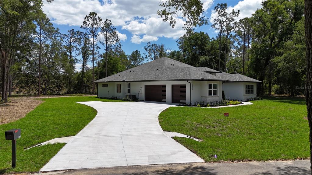 A single-story house with a white exterior, a gray shingled roof, and a concrete driveway — 24950 BONSMARA DRIVE, GROVELAND, FL