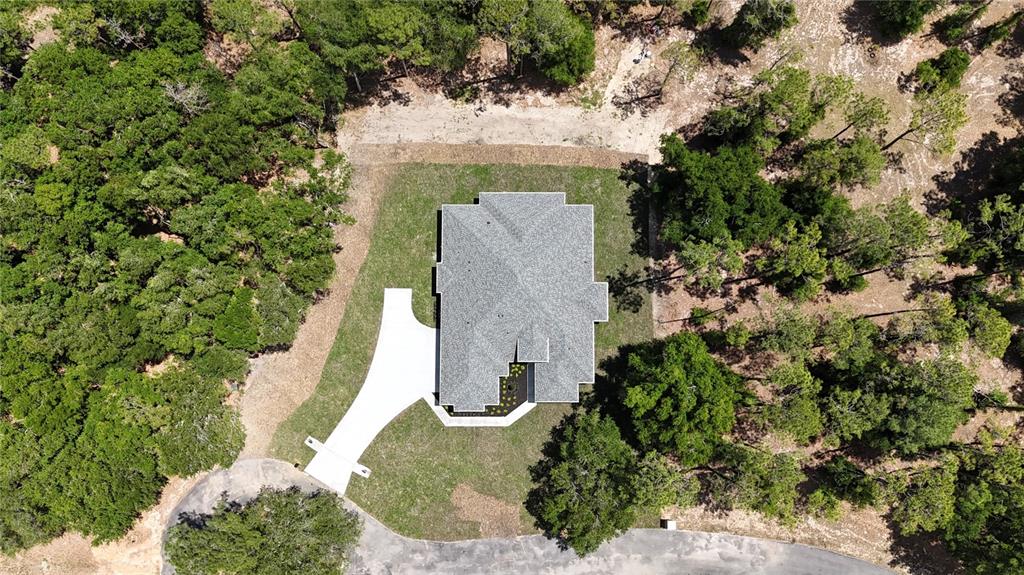 An aerial view shows a house with a gray roof surrounded by dense forest — 24950 BONSMARA DRIVE, GROVELAND, FL