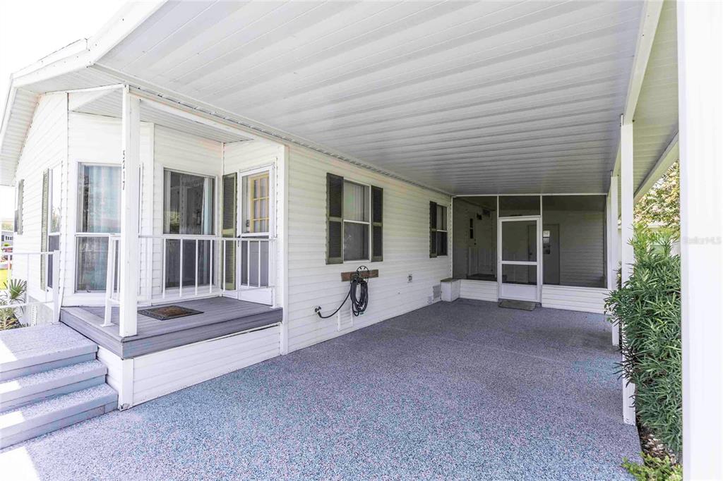 A white mobile home exterior features a covered carport, a small front porch, and siding — 5217 CAMBRIDGE COURT, WILDWOOD, FL