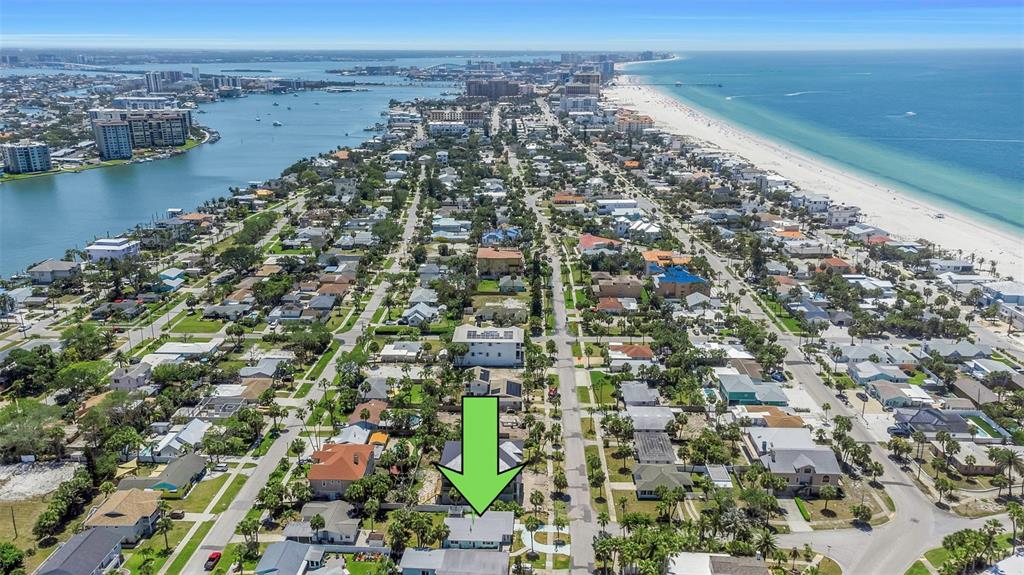 An aerial view shows a coastal neighborhood with a green arrow pointing to a house — 875 BRUCE AVENUE, CLEARWATER, FL
