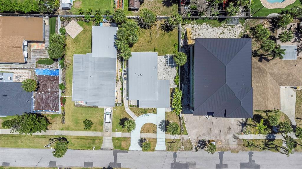 An aerial view shows three residential properties with houses, driveways, and landscaping along a street — 875 BRUCE AVENUE, CLEARWATER, FL