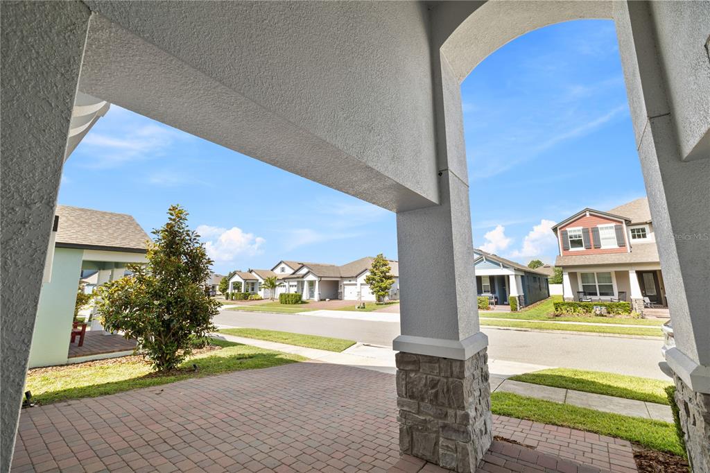 A view from a covered porch looking out onto a suburban residential street — 12241 ENCORE AT OVATION WAY, WINTER GARDEN, FL