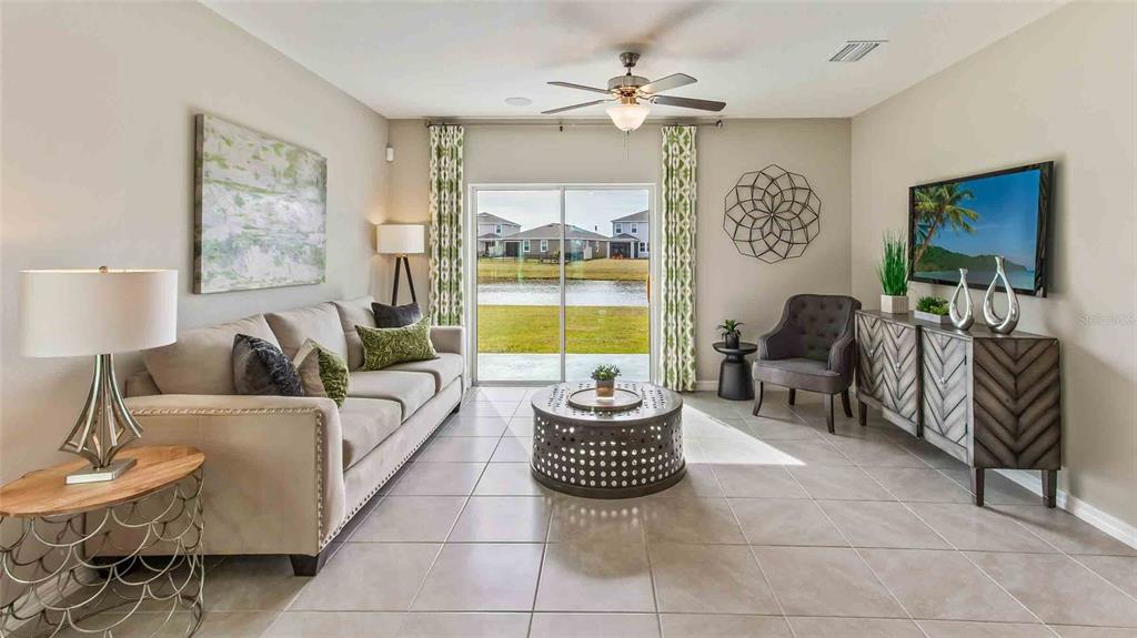 A living room features a beige sofa, a circular coffee table, and sliding glass doors — 32370 WEATHERED OAK DRIVE, WESLEY CHAPEL, FL