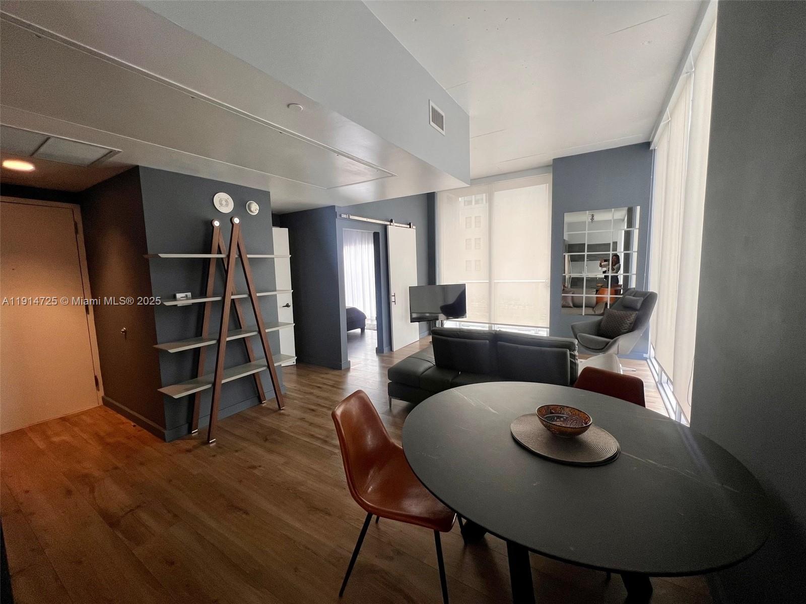 A modern living and dining area features dark walls, wood flooring, and a round table — 151 SE 1st St # 810, Miami FL 33131, MIAMI, FL