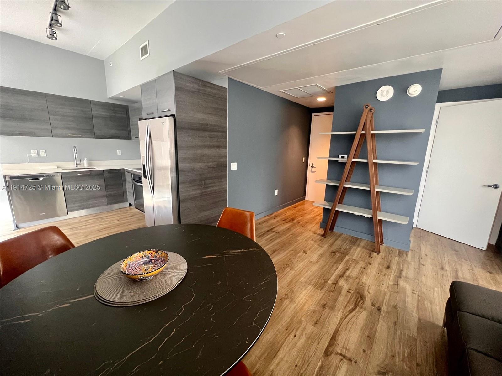 A kitchen with dark cabinetry and a dining area featuring a round table and shelving — 151 SE 1st St # 810, Miami FL 33131, MIAMI, FL
