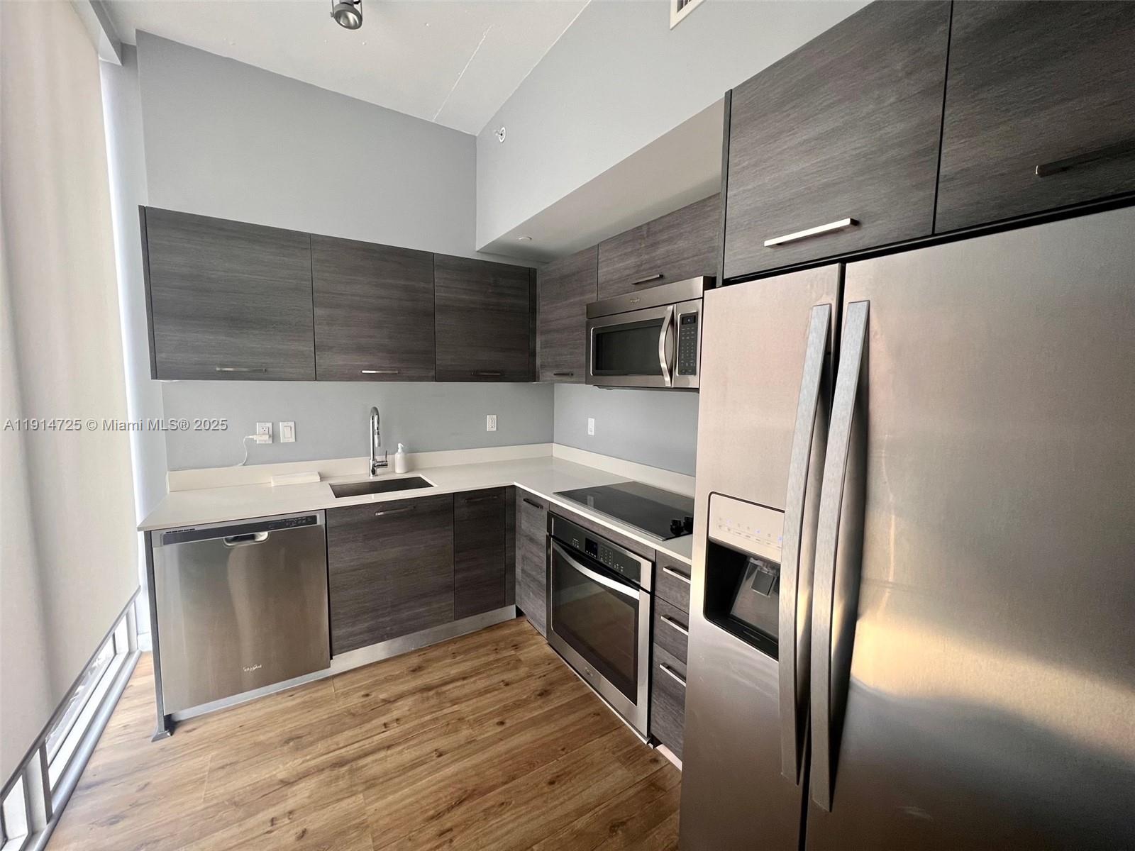 A modern kitchen features dark wood cabinets, stainless steel appliances, and light-colored countertops — 151 SE 1st St # 810, Miami FL 33131, MIAMI, FL