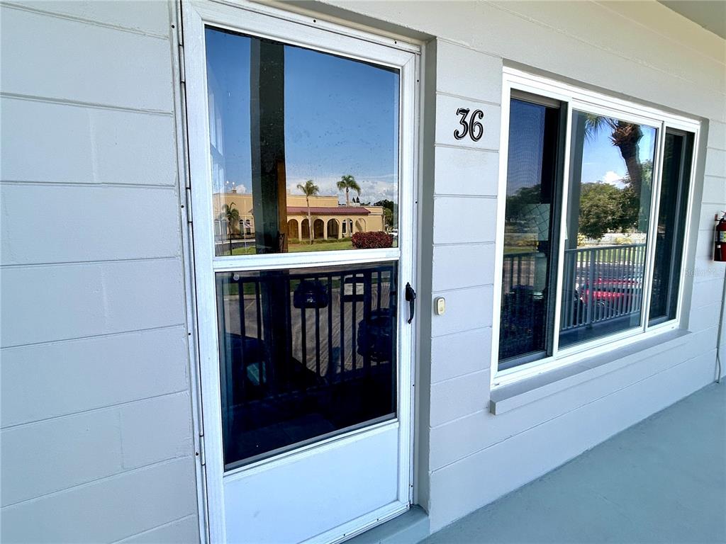 A white exterior wall features a screen door and a window labeled with the number 36 — 2070 WORLD PARKWAY BOULEVARD UNIT 36, CLEARWATER, FL