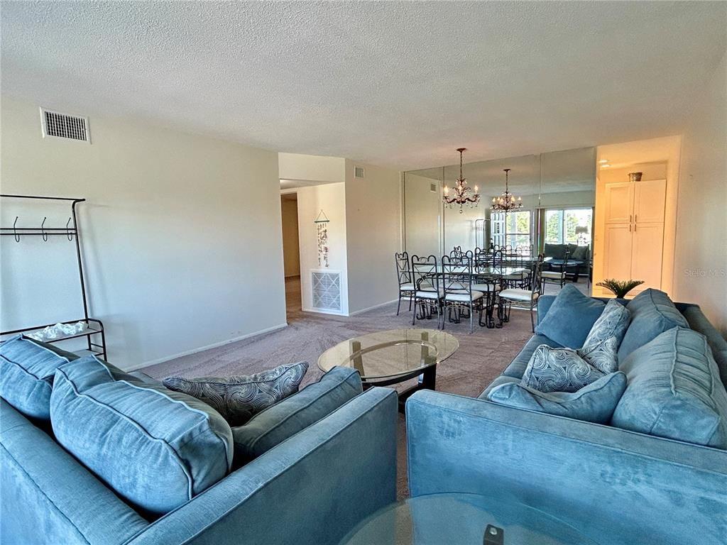 A living room and dining area with blue sofas, a glass coffee table, and mirrored walls — 2070 WORLD PARKWAY BOULEVARD UNIT 36, CLEARWATER, FL