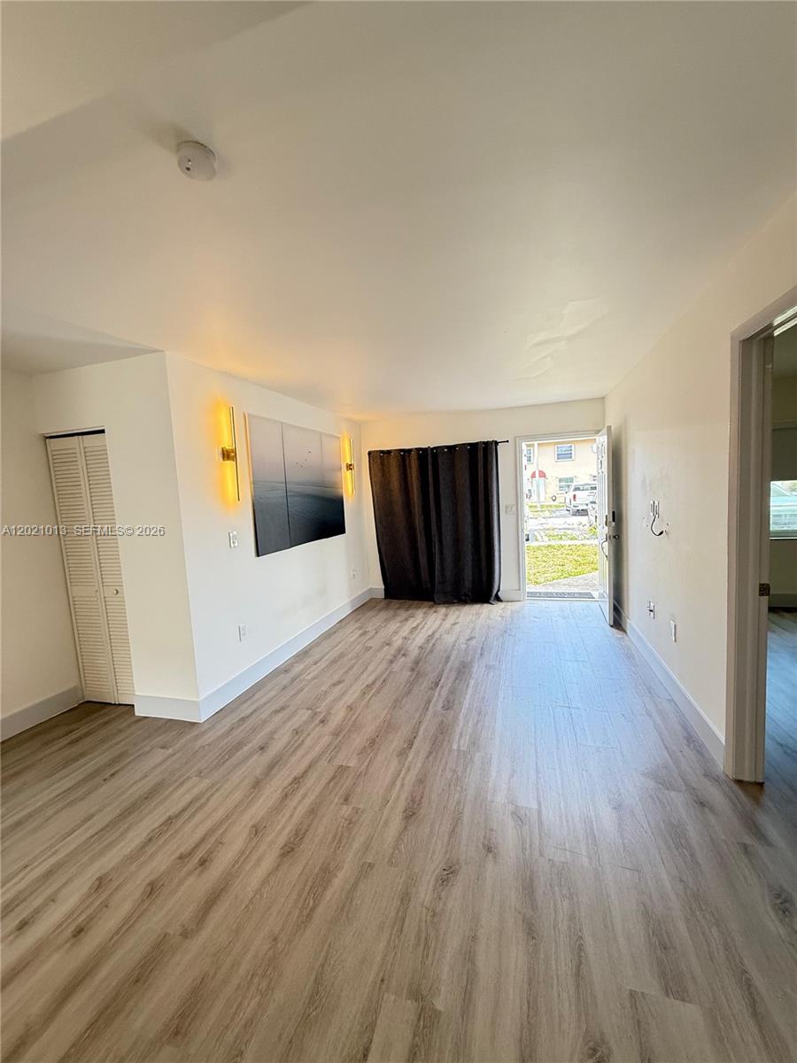 A living room features light wood-look flooring, white walls, a closet, and an open doorway — 15250 SW 80th St # 9, Miami FL 33193, MIAMI, FL