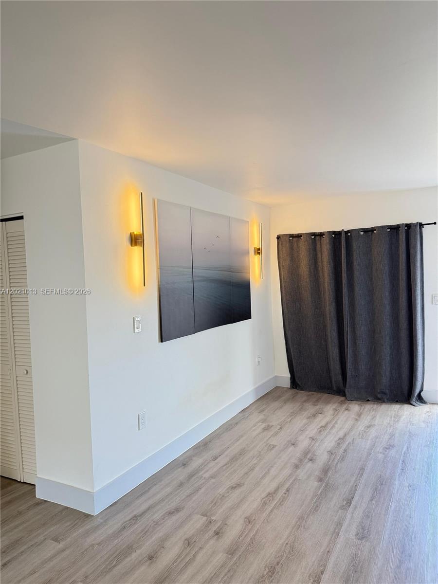 A room with light wood-look flooring, white walls, wall sconces, a triptych painting, and curtains — 15250 SW 80th St # 9, Miami FL 33193, MIAMI, FL