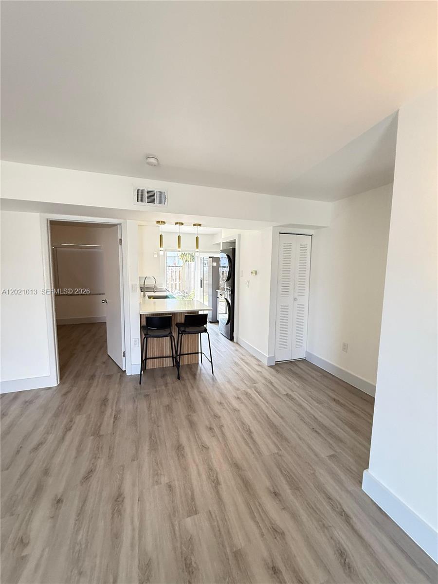 A living area with light wood-look flooring leads to a kitchen with a breakfast bar — 15250 SW 80th St # 9, Miami FL 33193, MIAMI, FL