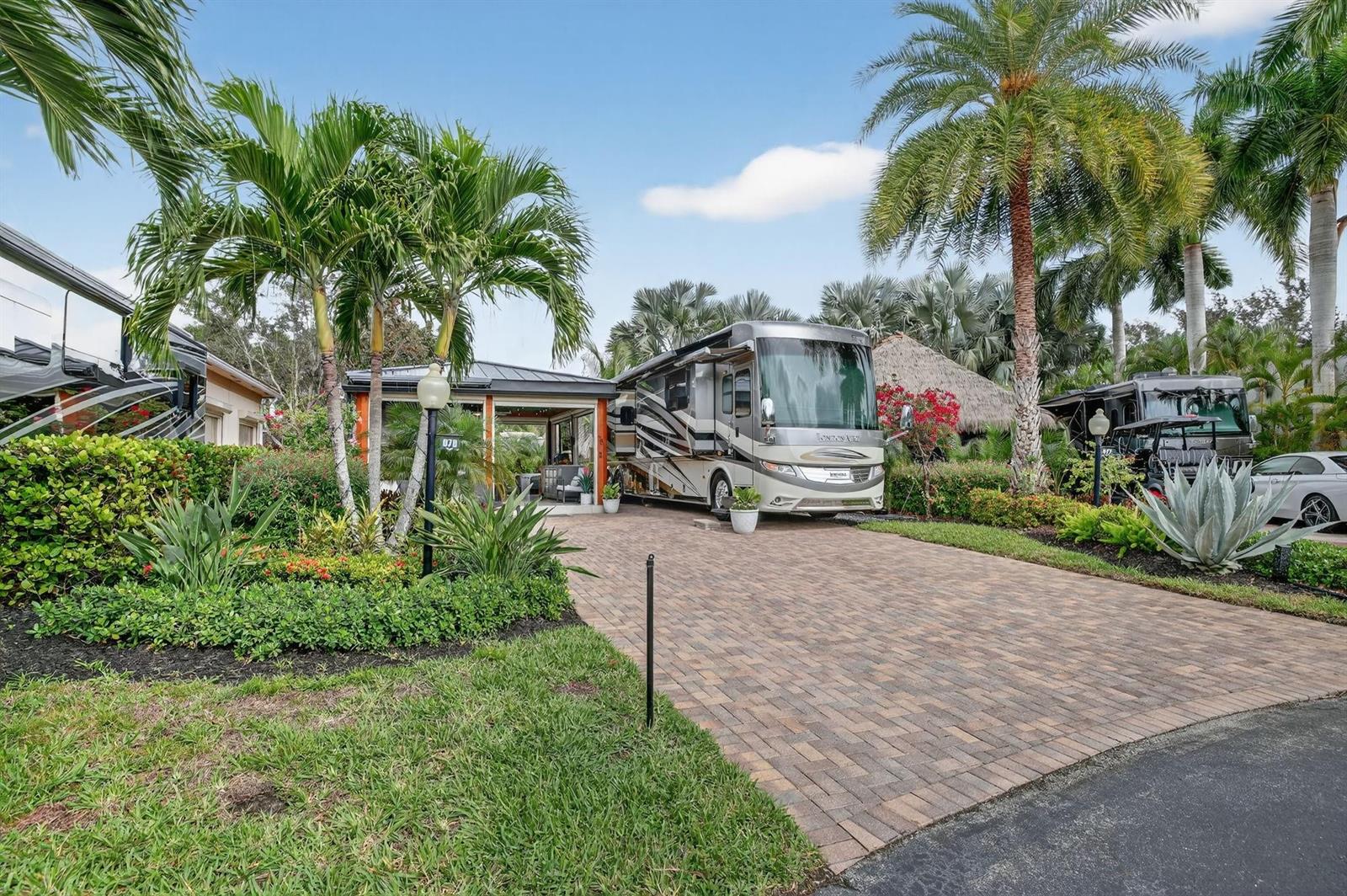 A large recreational vehicle is parked on a brick driveway next to a tropical patio — 78 S Cortez Drive # 78, Pompano Beach FL 33068, POMPANO BEACH, FL