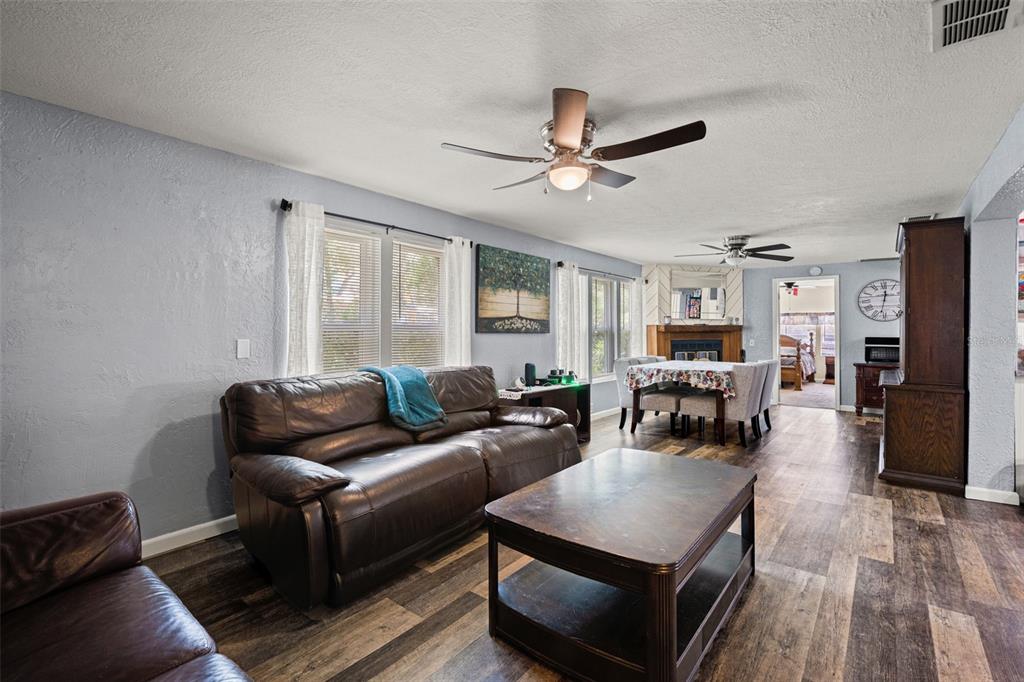 A living room with a brown leather sofa, coffee table, and dining area in the background — 8343 YELLOW PINE AVENUE, BROOKSVILLE, FL