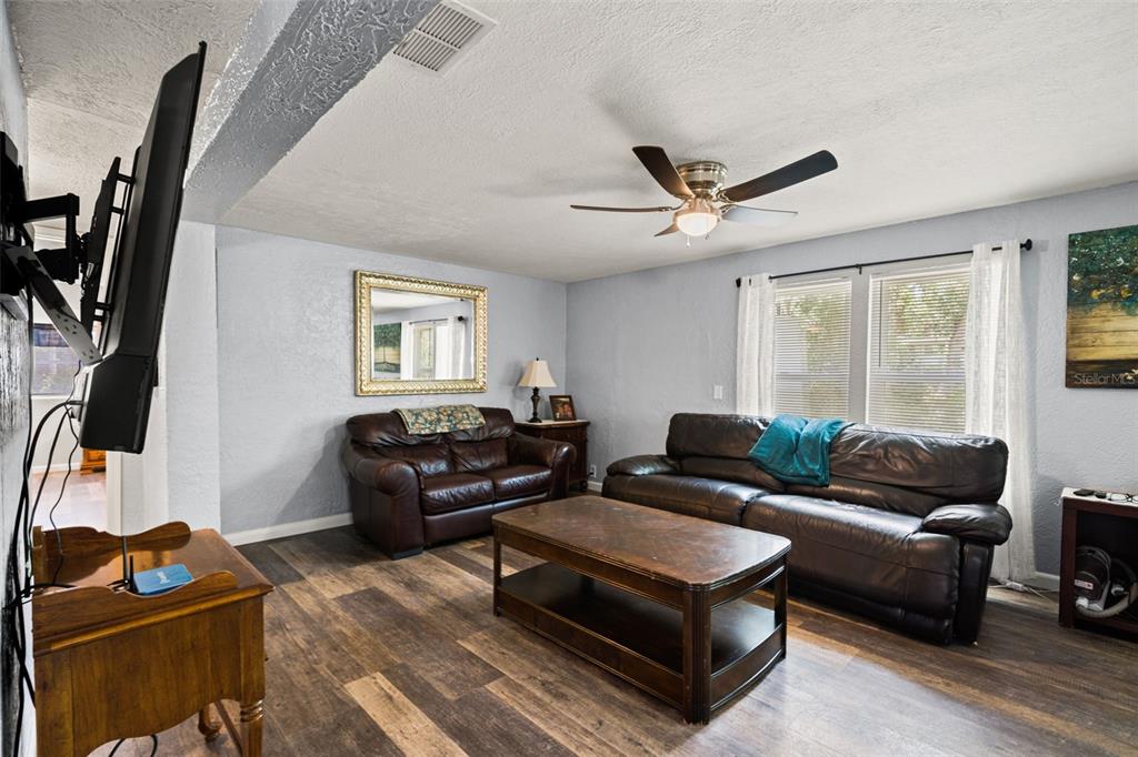 A living room features dark leather furniture, a wooden coffee table, and light blue walls — 8343 YELLOW PINE AVENUE, BROOKSVILLE, FL