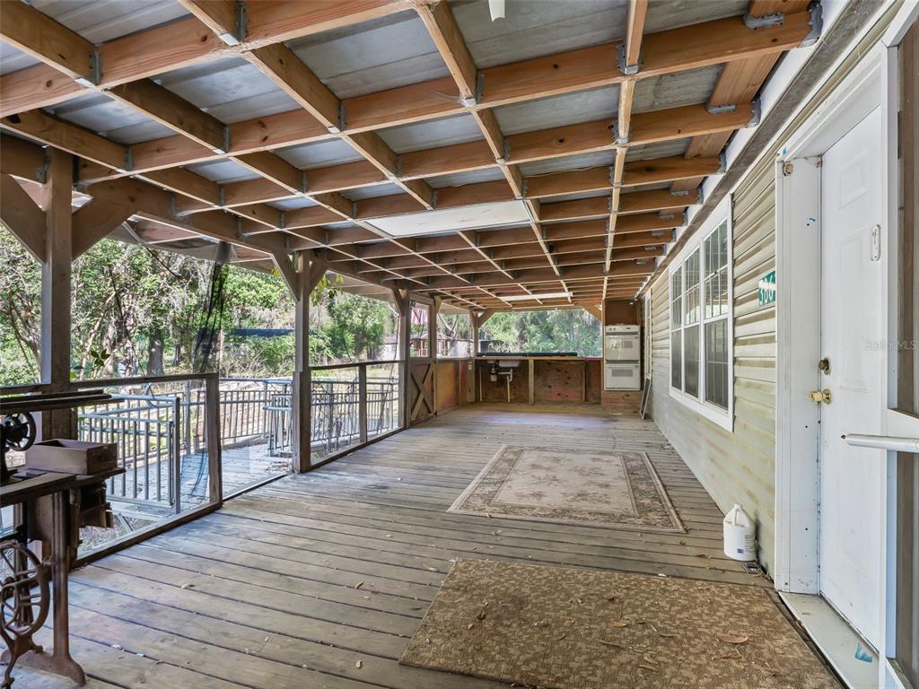 A covered wooden deck features exposed ceiling joists, screen walls, and a wooden gate — 3861 CR 519, COLEMAN, FL