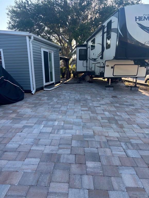 A paved patio area sits between a small gray building and a parked recreational vehicle — 20285 US HWY 27 UNIT 103, CLERMONT, FL