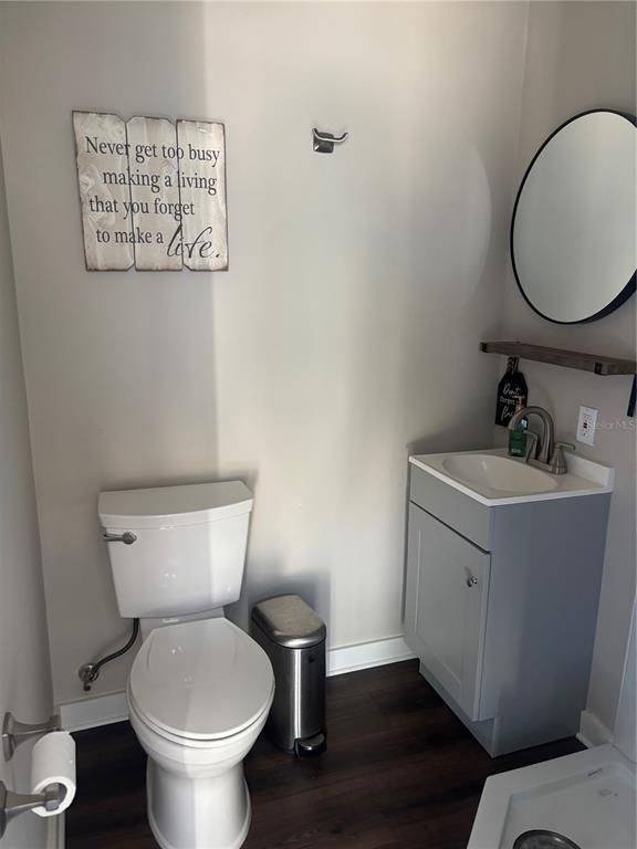 A small bathroom features a toilet, a gray vanity with a sink, and wall decor — 20285 US HWY 27 UNIT 103, CLERMONT, FL