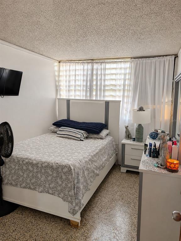 A bedroom features a white bed, a nightstand with a lamp, and a dresser — 9444 RIO CRISTAL UNIT 01, MAYAGUEZ, PR