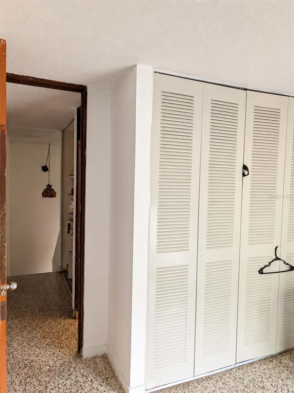 A view of a hallway with terrazzo flooring leading to a closet with louvered doors — 9444 RIO CRISTAL UNIT 01, MAYAGUEZ, PR