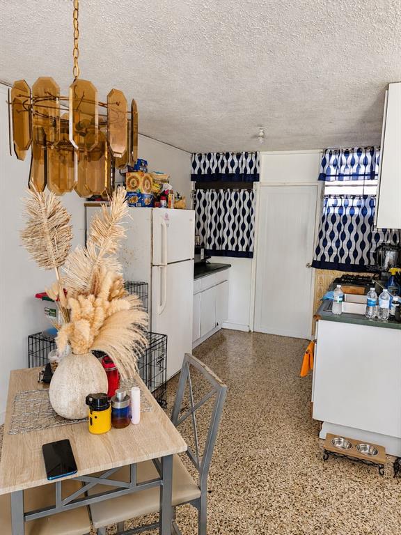 A kitchen features a dining table, a white refrigerator, and patterned blue and white curtains — 9444 RIO CRISTAL UNIT 01, MAYAGUEZ, PR