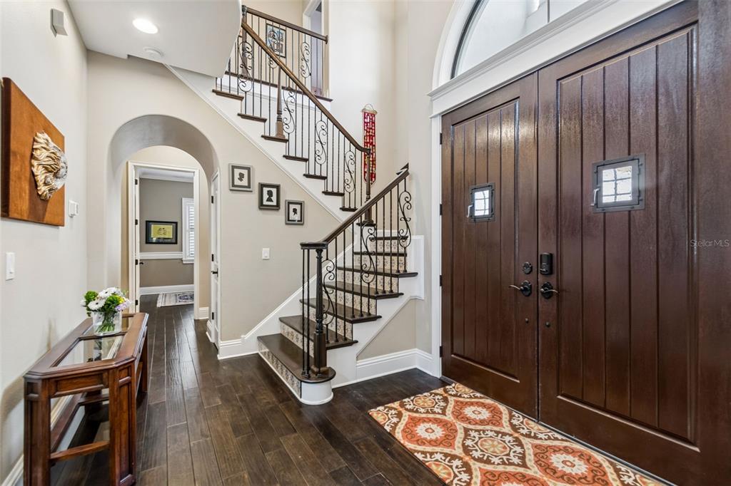 An entryway features a dark wood double door, a staircase with iron railings, and hardwood floors — 6011 S 3RD STREET, TAMPA, FL