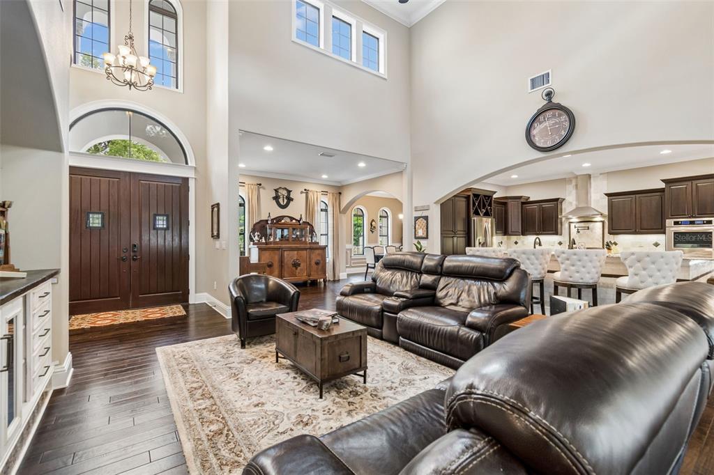 A spacious living room features dark wood floors, leather furniture, and a high vaulted ceiling — 6011 S 3RD STREET, TAMPA, FL