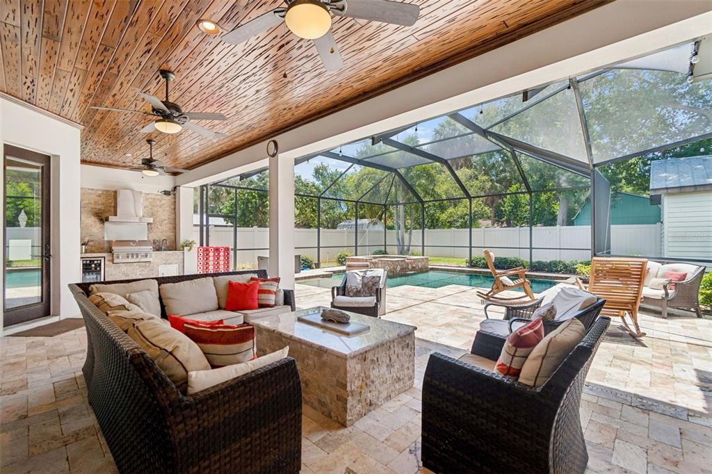 A covered outdoor patio features a stone fireplace, wicker furniture, and a screened-in swimming pool — 6011 S 3RD STREET, TAMPA, FL