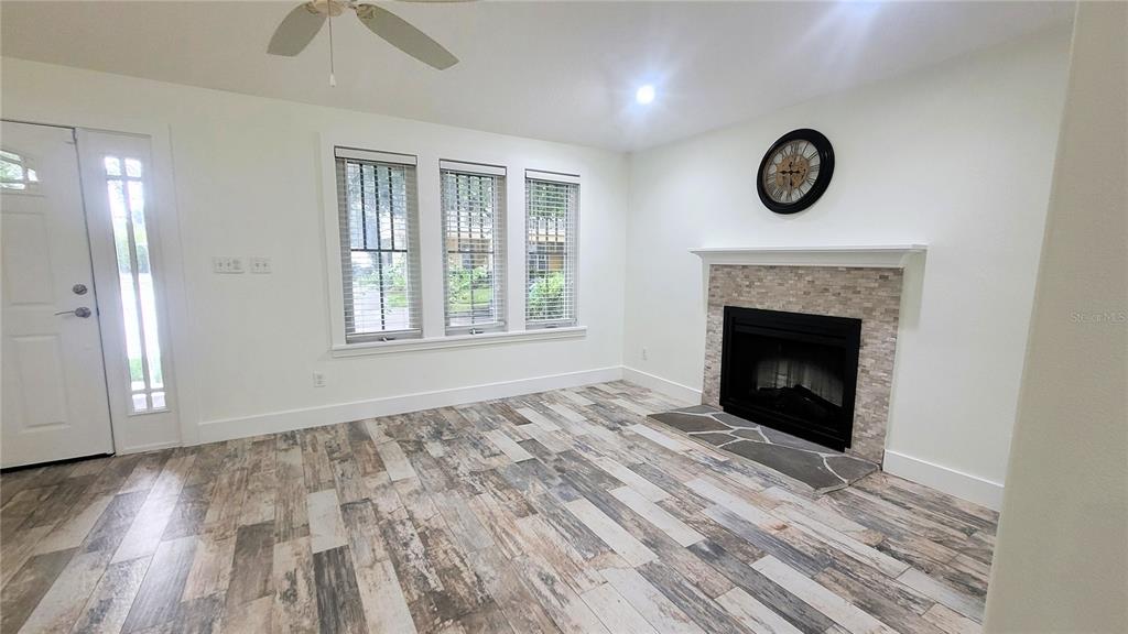 A living room features wood-look tile flooring, a fireplace with stone accents, and three windows — 1837 HOLLENBECK DRIVE, ORLANDO, FL