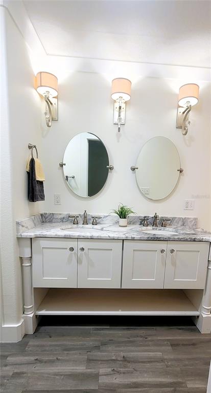 A double-sink bathroom vanity with white cabinets, marble countertops, and two oval mirrors — 1837 HOLLENBECK DRIVE, ORLANDO, FL