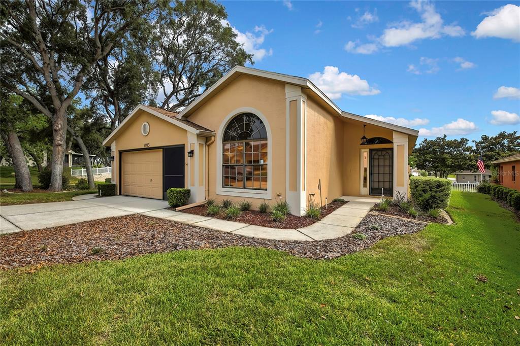 A single-story tan house with a garage, arched window, and a concrete walkway — 11103 CHERRYWOOD COURT, SPRING HILL, FL